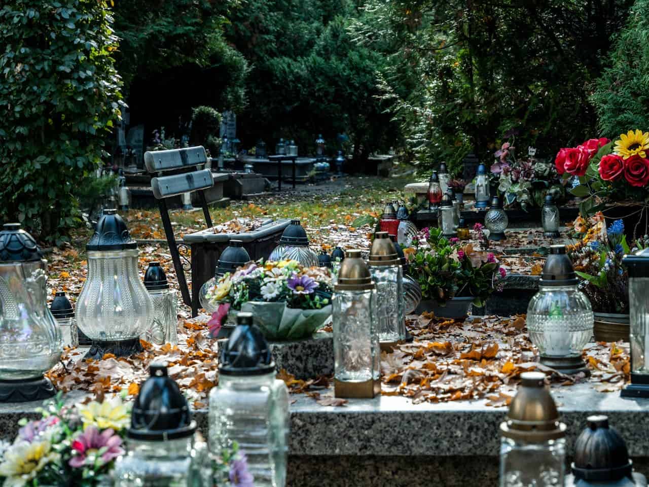 Serene cemetery scene with candles and flowers on a grave during fall.